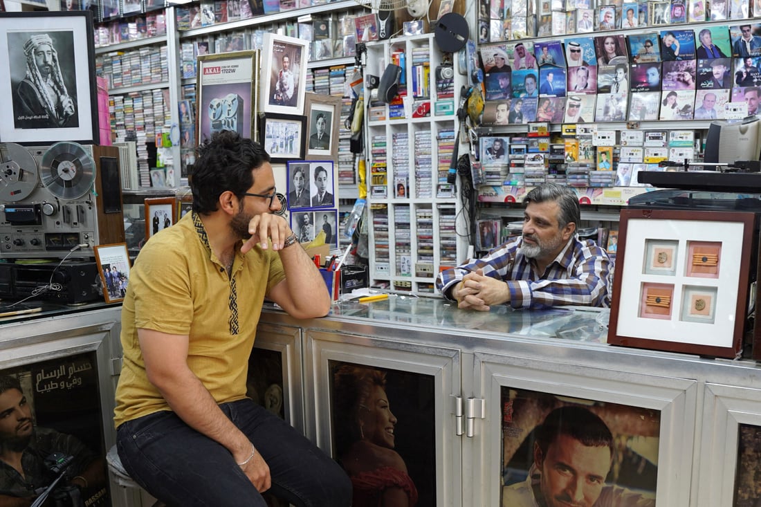 Iraqi music shop owner Amar Kheder (R) talks with a client at his store on May 16, 2024 in Mosul (Photo by Zaid AL-OBEIDI / AFP)