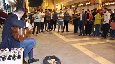 رواد المتنبي يتزاحمون لسماع الموسيقى قرب عازف عود من الهواة ويغدقون عليه المال