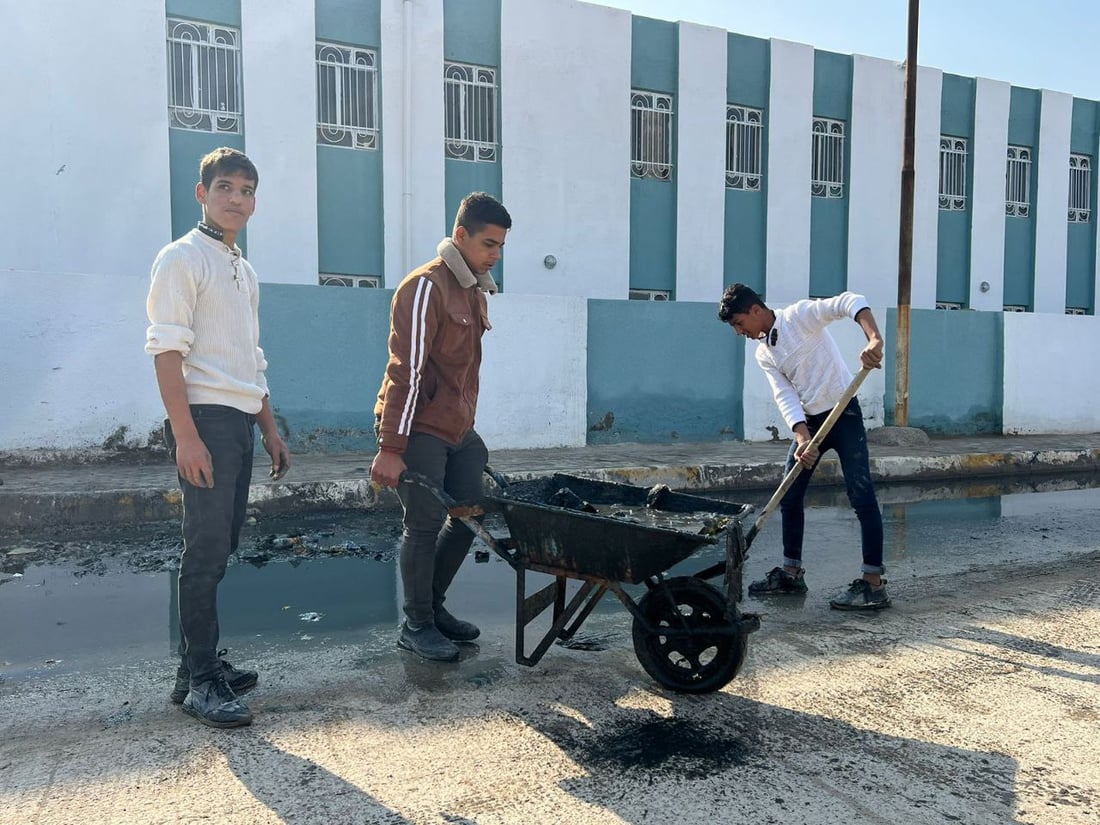 بابل: طلبة المدحتية سئموا الجدل بين البلدية والمجاري ونظفوا مدخل المدرسة (صور)