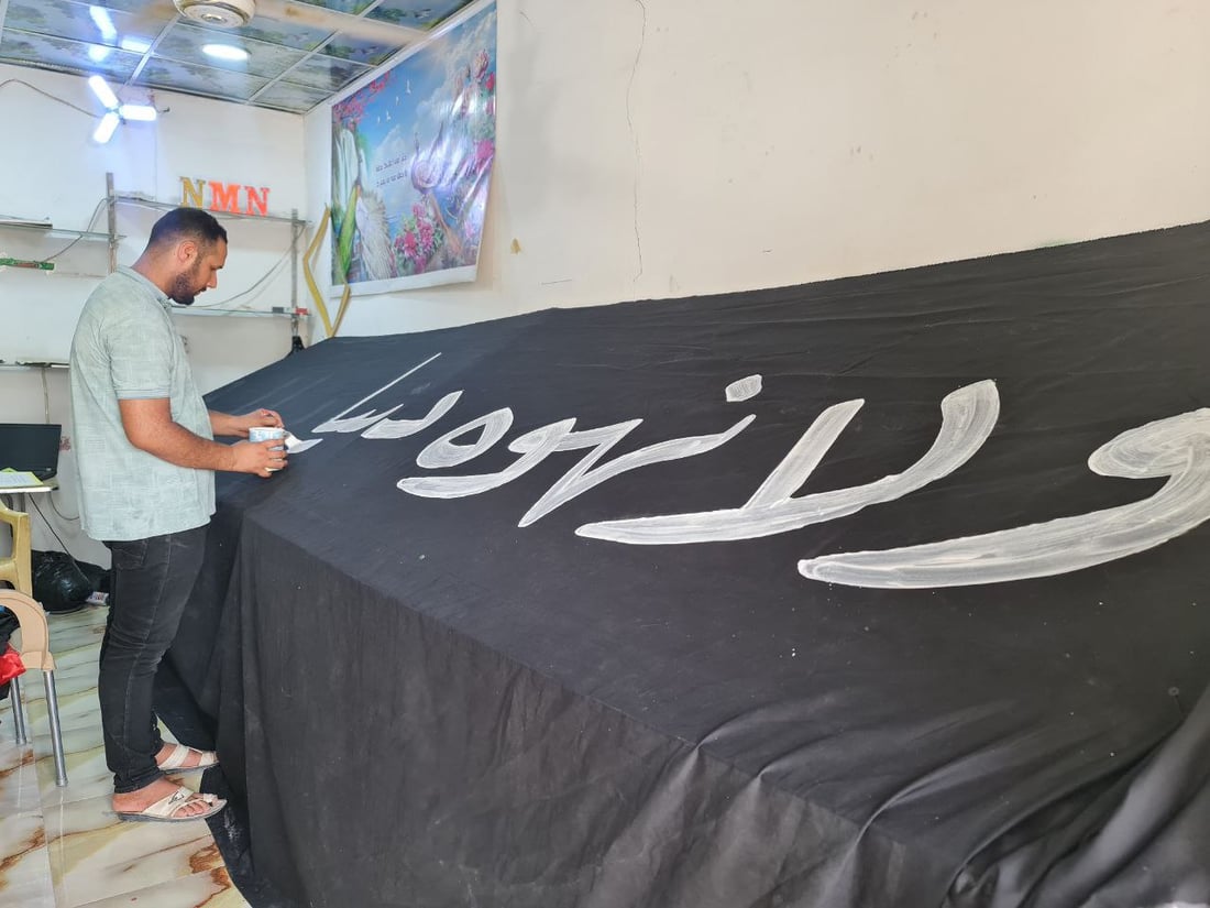 أصباغ أردنية تخط رايات الحسين في السماوة.. صور مع خطاطي شارع الجسر