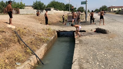 گەنجانی سەنگەسەر لە نەبوونی مەلەوانگە لەناو جۆگەی کشتوکاڵیدا مەلەدەکەن