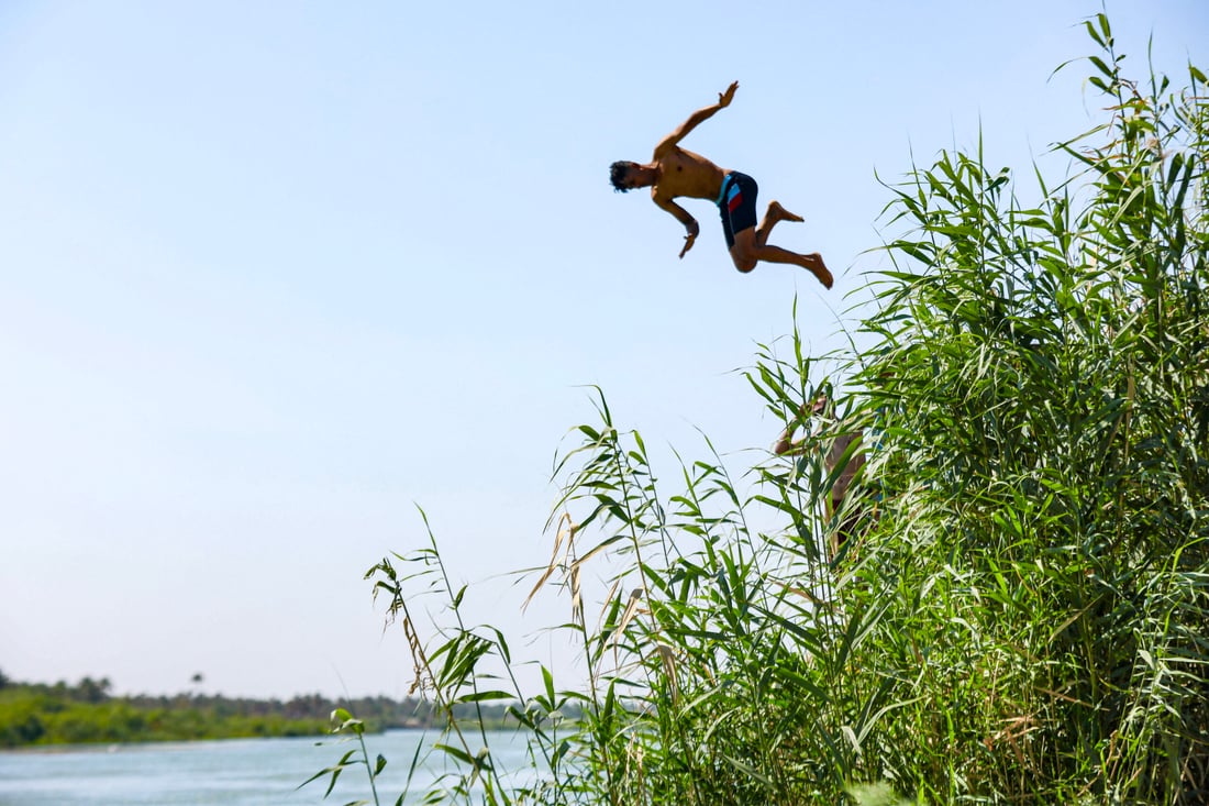 A youth dives into the waters of Iraq's Euphrates river to cool off during a heatwave (Photo by Karar JABBAR / AFP)