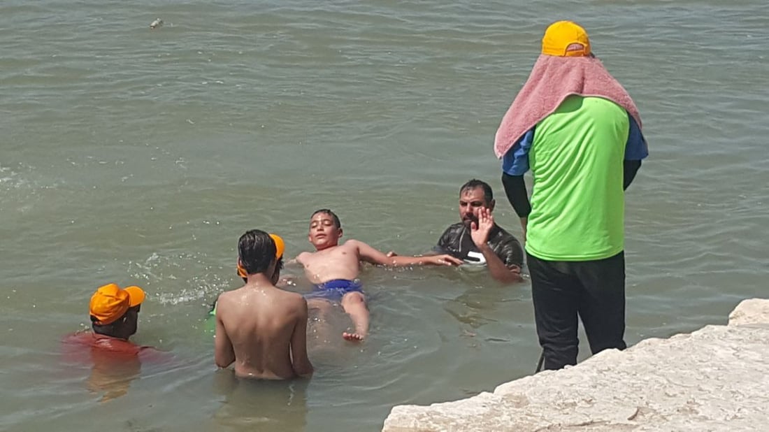 على شط المسيب ومع برودة الفرات.. سباح دولي يدرب الأطفال (صور)