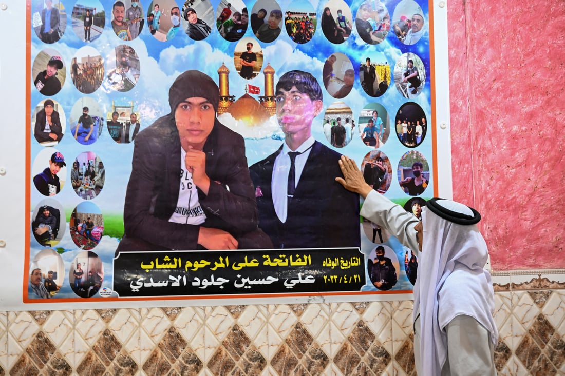 Hussein Julood touches a portrait of his late son at home (Photo by Hussein FALEH / AFP)