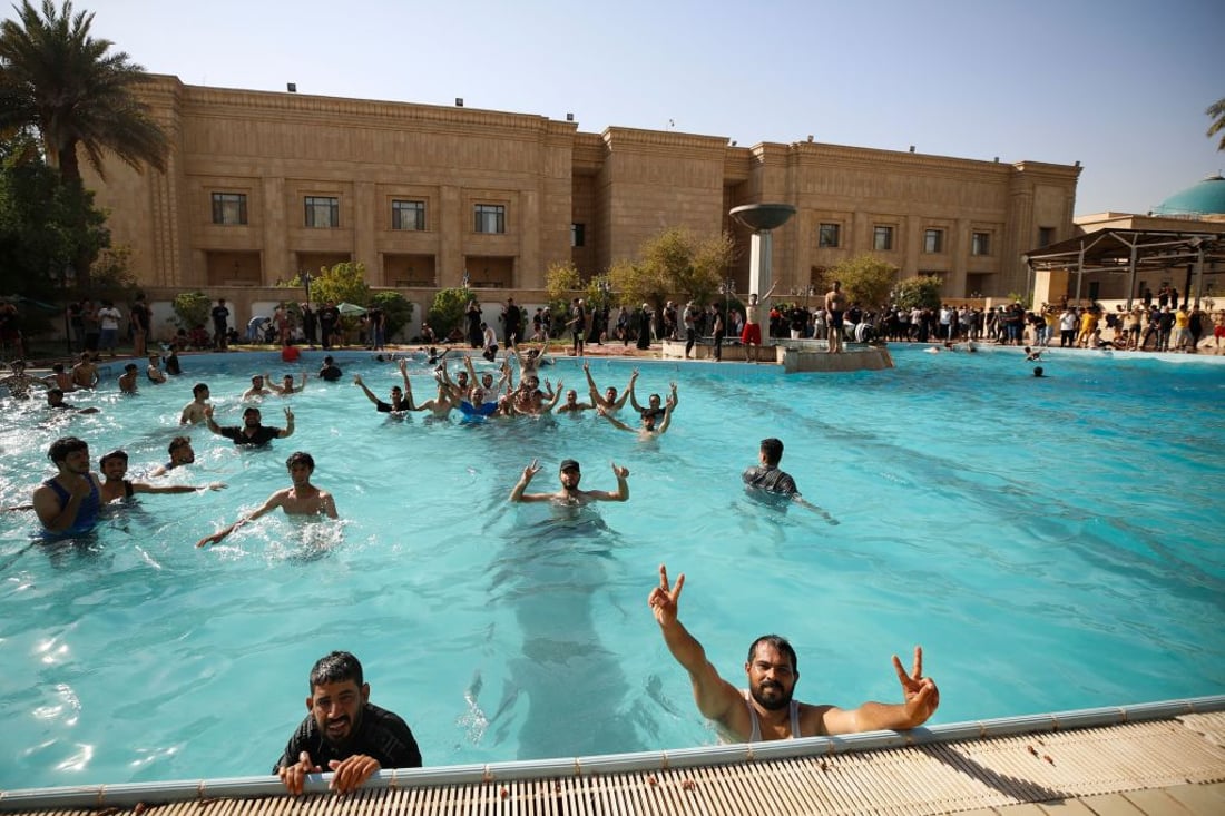 Supporters of Iraqi Shiite cleric Moqtada Sadr swim in the pool of the Government Headquarters in the capital Baghdad's Green Zone, on August 29, 2022. - Dozens of angry supporters of the powerful cleric stormed the Republican Palace, a ceremonial building in the fortified Green Zone, a security source said, shortly after Sadr said he was quitting politics. The army has announced a  Baghdad-wide curfew to start from 3:30 pm (1230 GMT). (Photo by Ahmad Al-rubaye / AFP) (Photo by AHMAD AL-RUBAYE/AFP via Getty Images)
