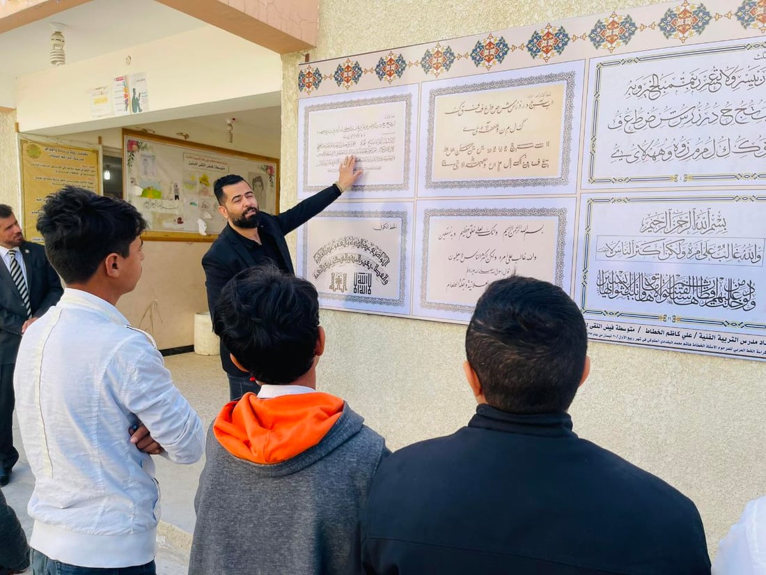صور: مدرّس شاب في سوق الشيوخ رسم 8 أنواع من الخط العربي على جدارية كبيرة