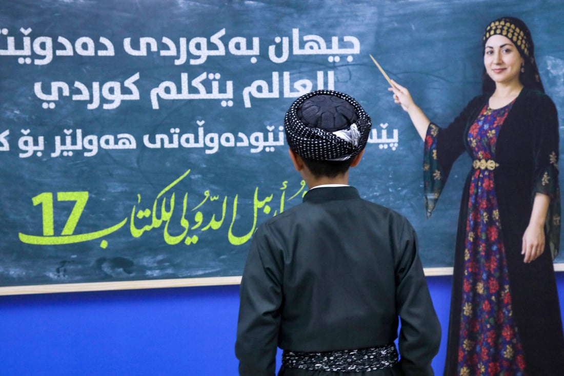 A young visitor stands in front of a poster during the 17th Arbil International Book Fair, in the capital of the autonomous Kurdish region of northern Iraq, on April 9, 2025. (Photo by Safin HAMID / AFP)