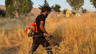 گەنجێک قۆڵی هەڵماڵیوە و گۆڕستانی پیرباڵ لە باتاس پاک دەکاتەوە