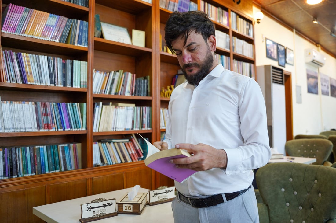 Azad Hassan, an Iraqi student who uses a prosthetic hand, is pictured taking notes in a library in Mosul on May 20, 2024 (Photo by Zaid AL-OBEIDI / AFP)