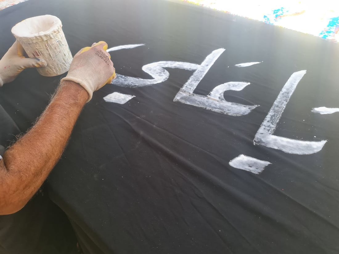 أصباغ أردنية تخط رايات الحسين في السماوة.. صور مع خطاطي شارع الجسر