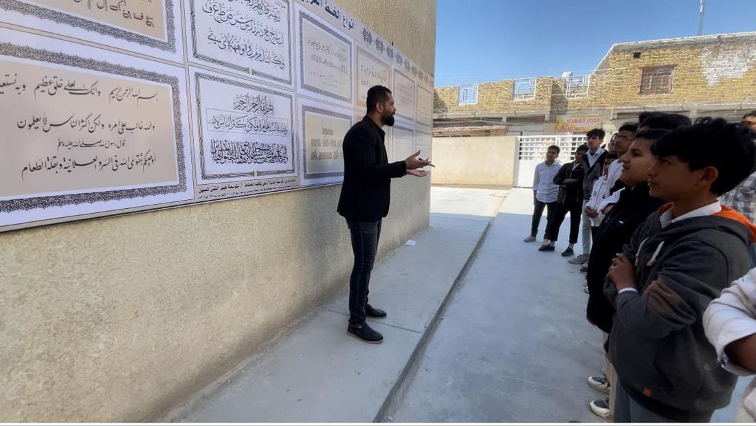 صور: مدرّس شاب في سوق الشيوخ رسم 8 أنواع من الخط العربي على جدارية كبيرة