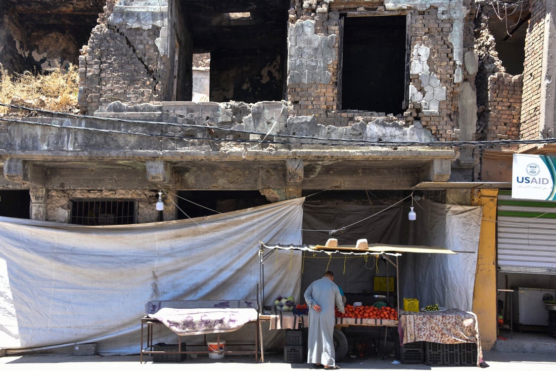 An Iraqi man sells vegetables in front of a building destroyed during the battles to defeat the Islamic State group, in the old city of Mosul in northern Iraq, on May 20, 2024. (Photo by Zaid AL-OBEIDI / AFP)