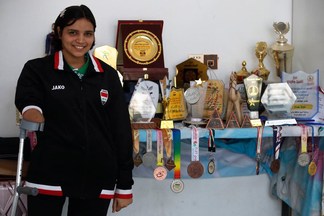 Iraqi paralympics table tennis athlete Najlah Imad, poses for a picture near her trophies and medals at her house (Photo by Ahmad AL-RUBAYE / AFP)
