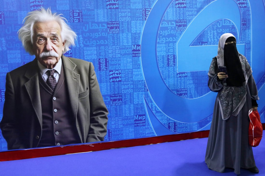 A visitor stands in front of a poster depicting late German-born physicist Albert Einstein during the 17th Arbil International Book Fair, in the capital of the autonomous Kurdish region of northern Iraq, on April 9, 2025. (Photo by Safin HAMID / AFP)