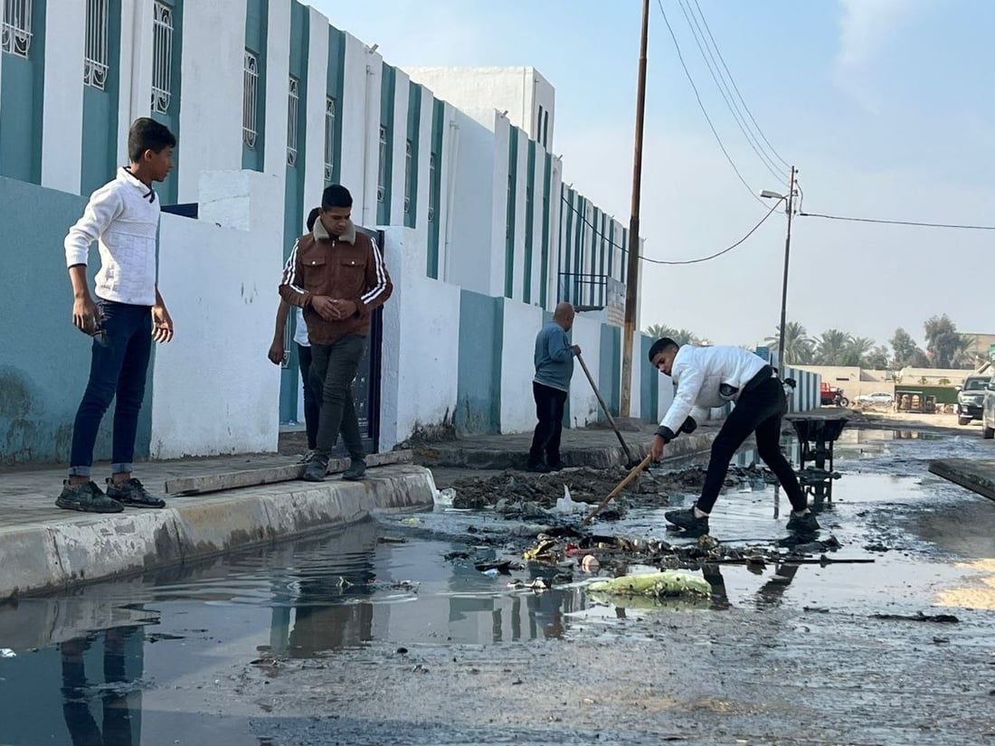 بابل: طلبة المدحتية سئموا الجدل بين البلدية والمجاري ونظفوا مدخل المدرسة (صور)
