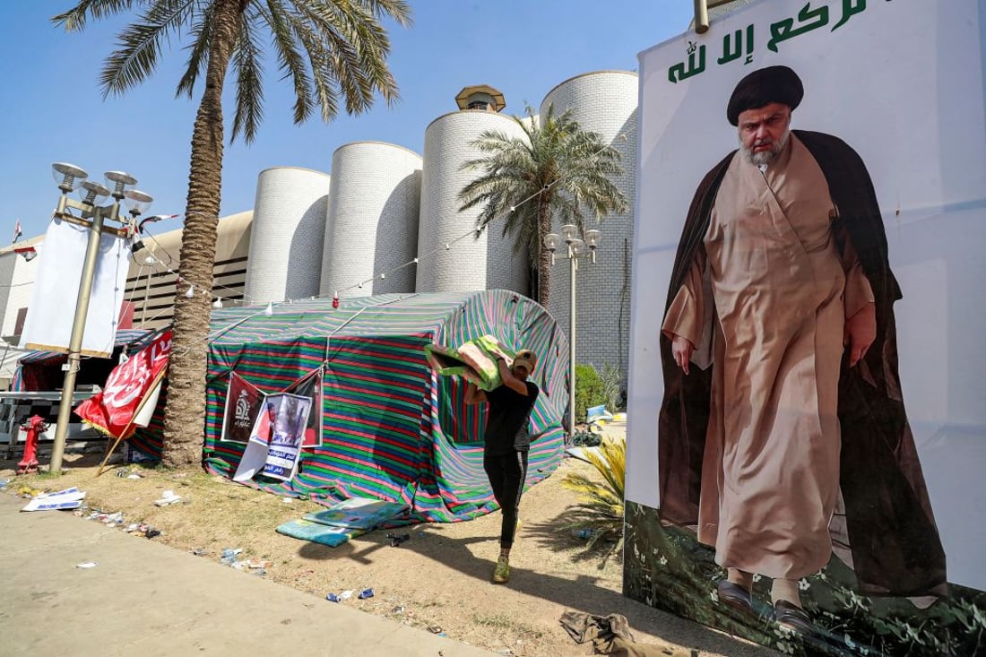 A supporter of Shiite Muslim cleric Moqtada al-Sadr carries away items as their encampment in Baghdad's high-security Green Zone is dismantled on August 30, 2022. - Members of the Sadrist faction began withdrawing from Baghdad's Green Zone on August 30 after their leader demanded fighting end between rival Shiite forces and the army that left 23 dead and hundreds wounded. (Photo by AHMAD AL-RUBAYE / AFP) (Photo by AHMAD AL-RUBAYE/AFP via Getty Images)