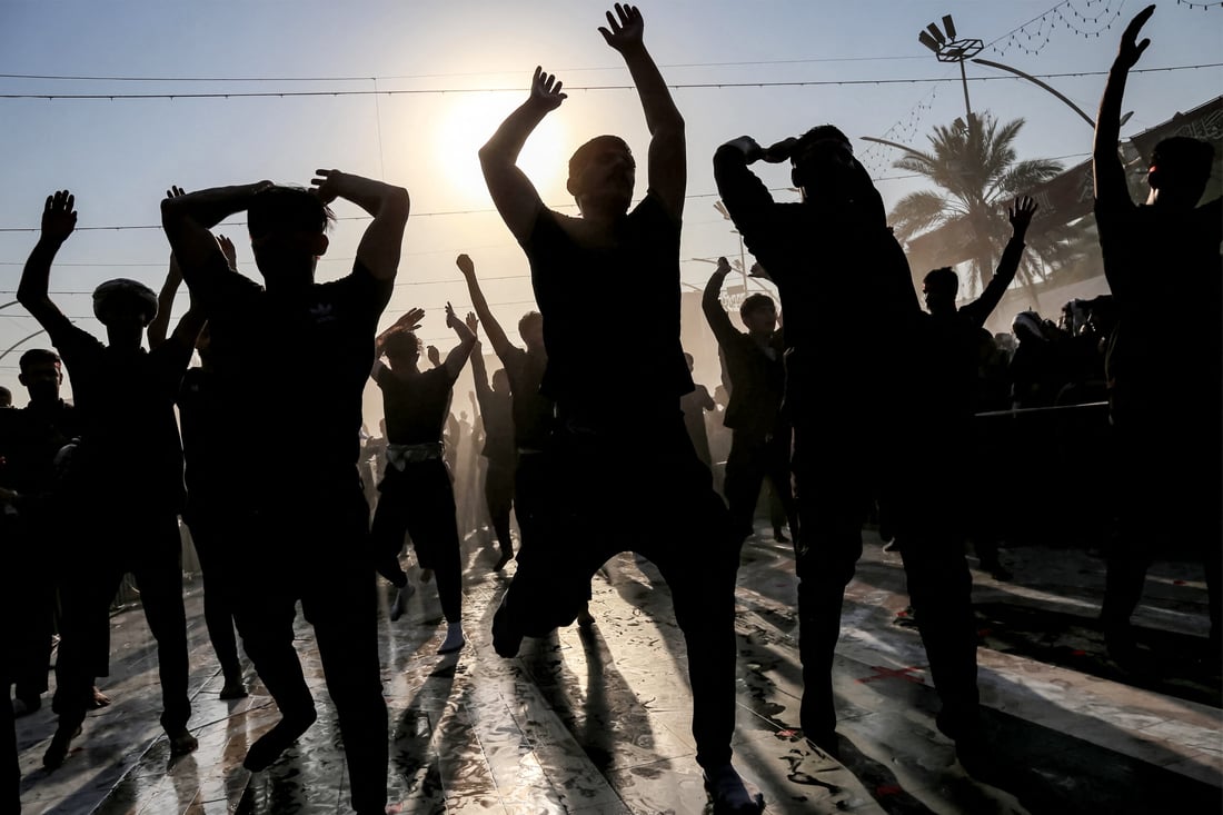 Shiite Muslim devotees react as they are sprayed with water vapour to cool off during extreme (Photo by Mohammed SAWAF / AFP)