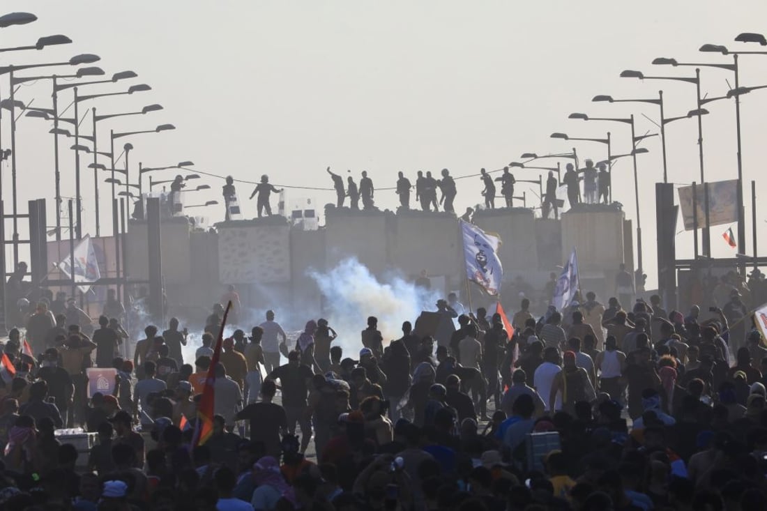 BAGHDAD, IRAQ - OCTOBER 01: Hundreds of Iraqis hold banners and shout slogans as they gather during a demonstration marking the third anniversary of the eruption of nationwide demonstrations against corruption, at the Tahrir Square in Baghdad, Iraq on October 01, 2022. Iraqi security forces responded with tear gas and sound bombs as protesters trying to break through the barriers on the Republic Bridge. (Photo by Murtadha Al-Sudani/Anadolu Agency via Getty Images)