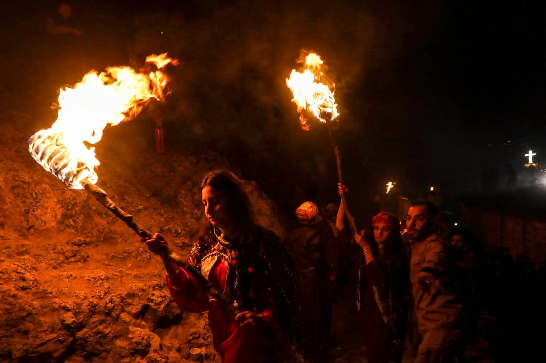 Iraqi Kurds march with torches during a procession to celebrate the Nowruz New Year festival in the town of Akre (Photo by Safin HAMID/AFP)