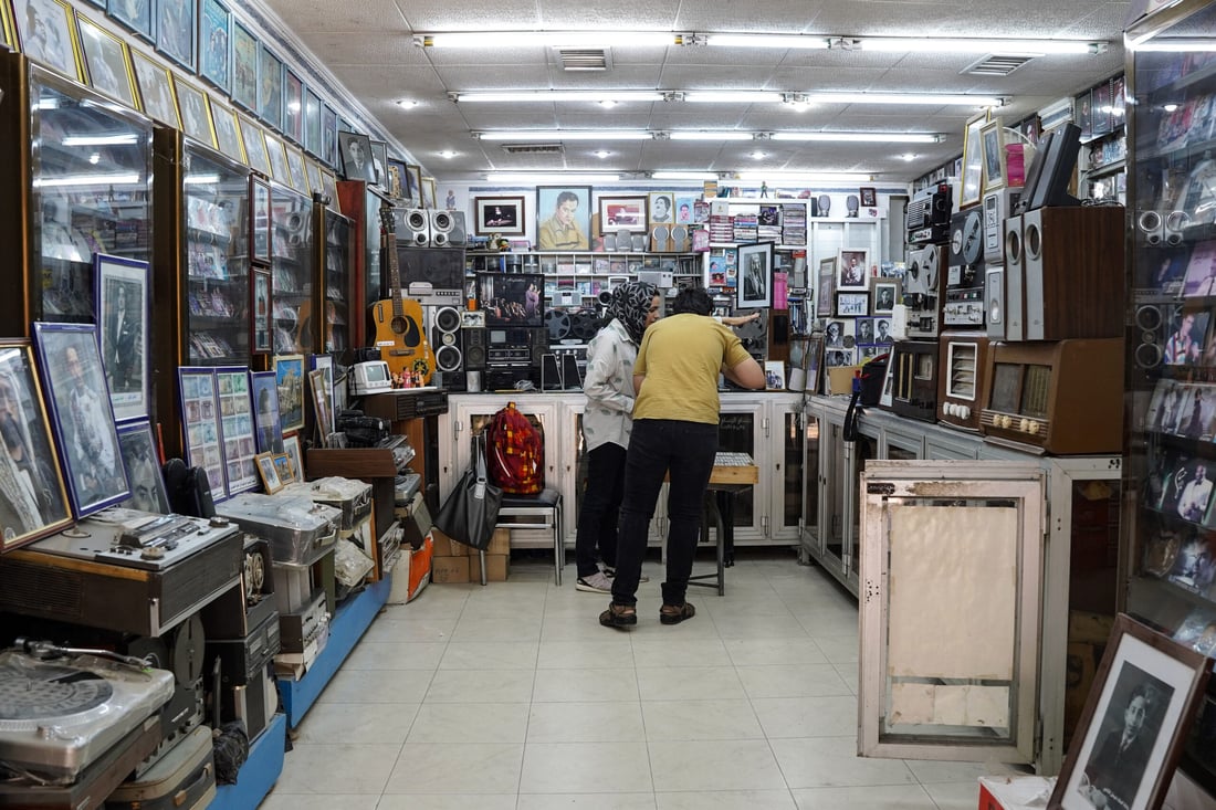 Iraqi music shop owner Amar Kheder (R) talks with a client at his store on May 16, 2024 in Mosul (Photo by Zaid AL-OBEIDI / AFP)
