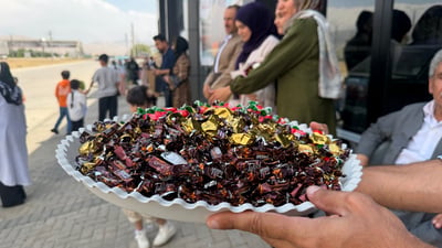 حاجى ژن بە باوەشێک گوڵەوە لە چاوەڕوانى حاجى مێردیدا وەستاوە